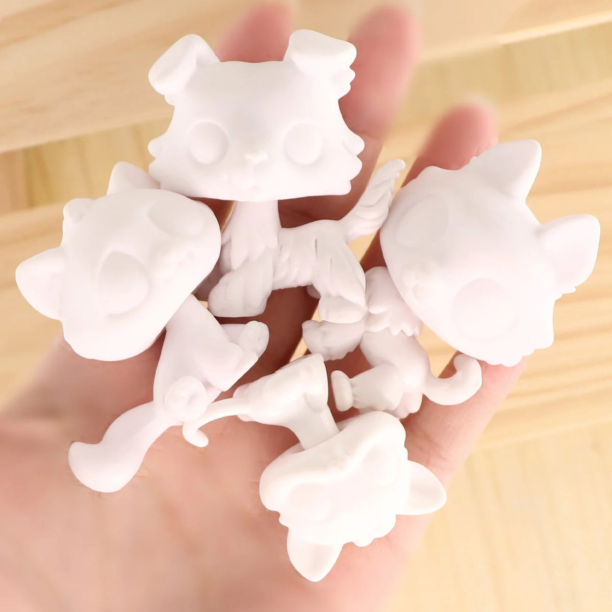 A hand holds a collection of white, customizable bobble head pet figures for a DIY kit.