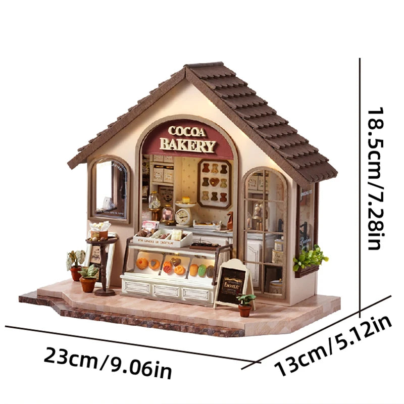 A miniature dollhouse kit featuring a cocoa bakery facade with detailed furniture and warm lighting.