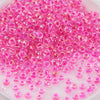 A pile of small, round pink and clear glass rice beads for DIY jewelry and crafting.
