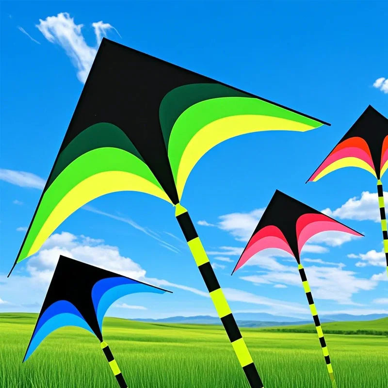 A large delta kite with a black and green canopy is flying against a bright blue sky over green fields.