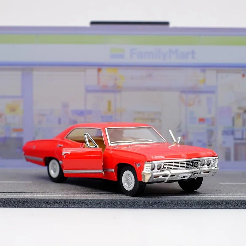 A red 1967 Chevrolet Impala diecast model car in pull-back action on a gray surface.