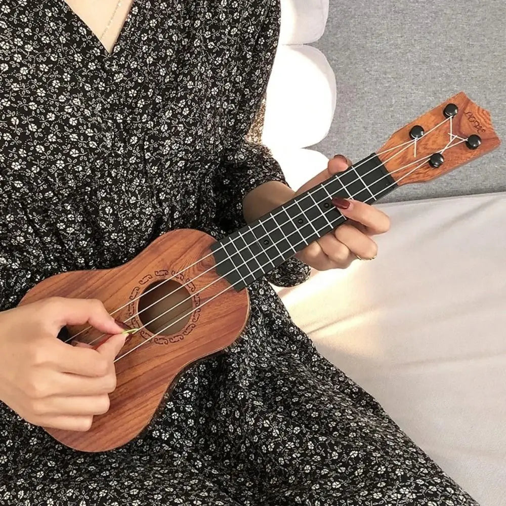 A person is playing a wooden ukulele toy with adjustable tuning pegs while wearing a black floral dress.