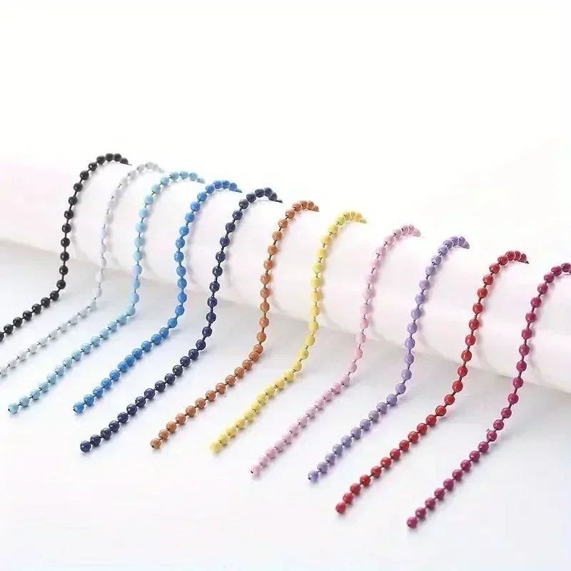 A collection of ball bead chains in various pastel colors, including blue, purple, and yellow, laid out for DIY jewelry.