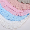 A stack of pink, blue, and white ruffled muslin cotton baby bibs.