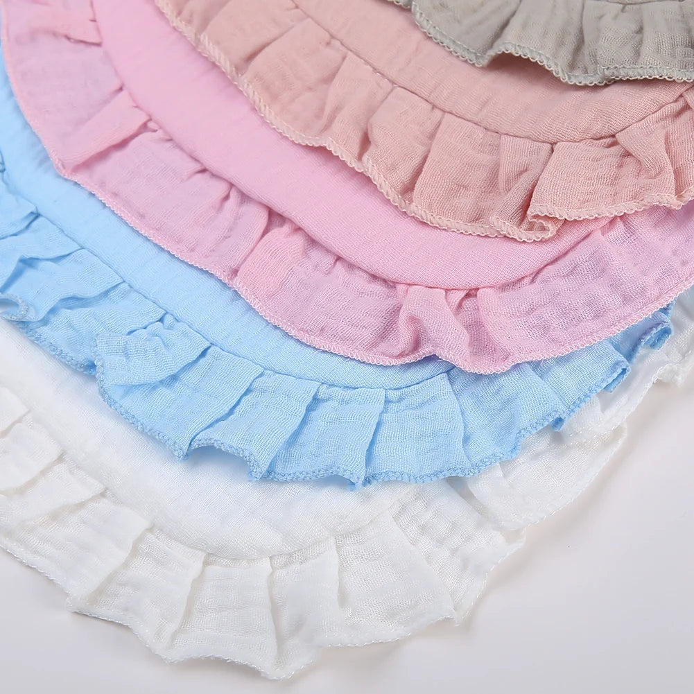 A stack of pink, blue, and white ruffled muslin cotton baby bibs.