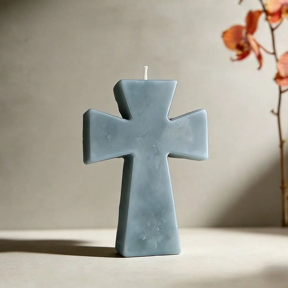 A light blue silicone cross mold for candles, soap, and resin crafts sitting on a surface.