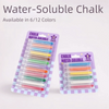 A display of water-soluble chalk pencils in various colors arranged in plastic packaging.