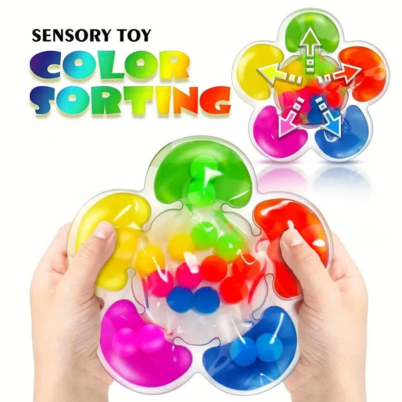 Hands hold a colorful sensory sorting toy with various colored balls and shapes.