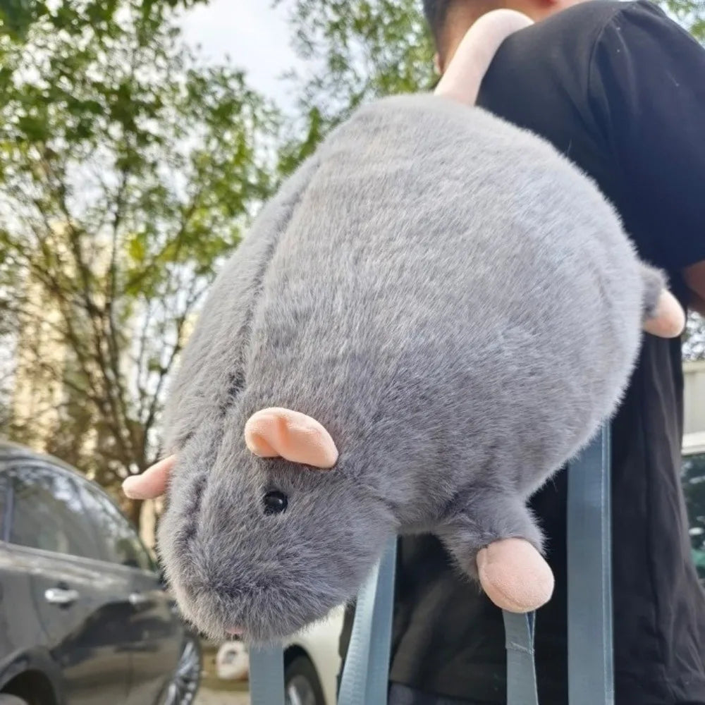A person is holding a gray mouse plush toy with pink ears and paws.