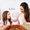 A girl and a woman interact with a wooden dice game on a table.
