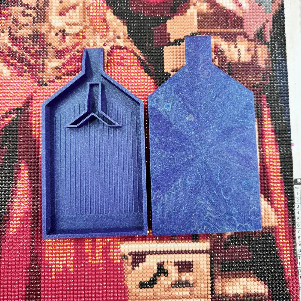 A pair of blue diamond painting trays with pop-up plugs displayed on a colorful beaded background.