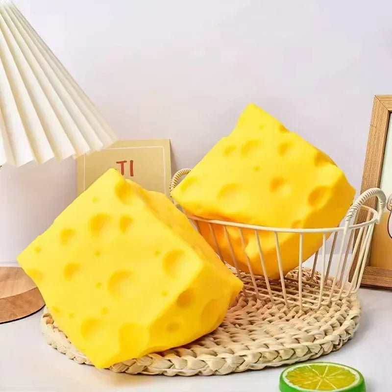 A bright yellow cheese wedge squishy stress relief toy resting on a woven mat.