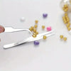 A set of six stainless steel precision tweezers with straight and bent tips resting on a white surface near various colored b