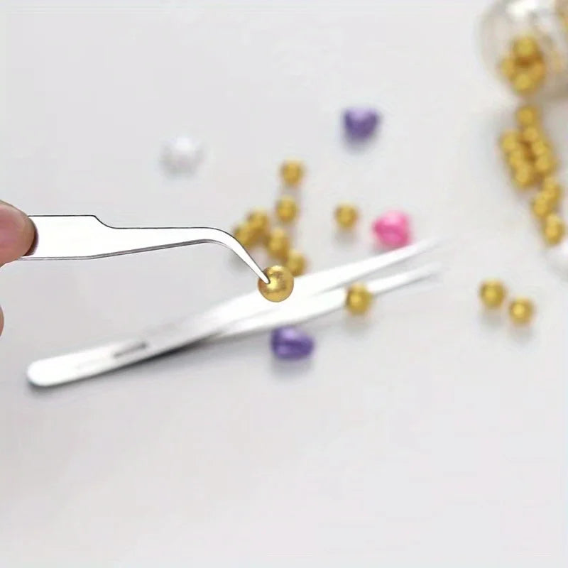 A set of six stainless steel precision tweezers with straight and bent tips resting on a white surface near various colored b