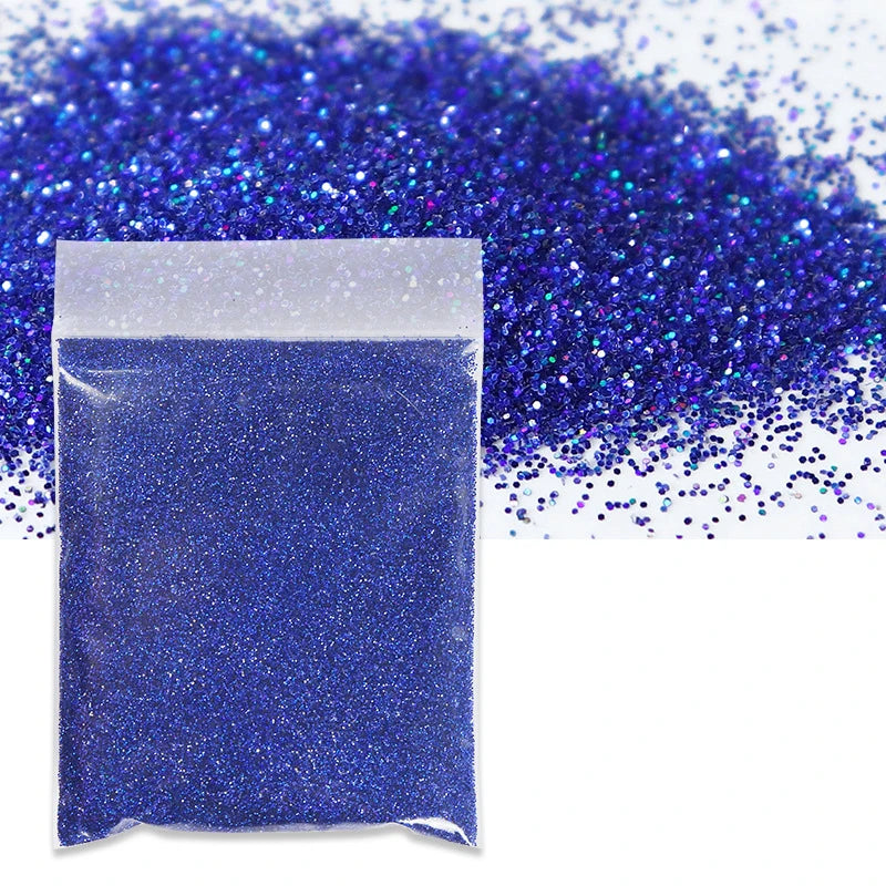 A small plastic bag filled with vibrant blue holographic glitter powder scattered across a white background.