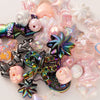 A collection of iridescent and pastel acrylic bow and flower beads for DIY jewelry making.
