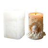 A lit candle in a decorative glass holder featuring an angel design with gold accents.