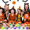 A set of five Halloween squeeze stress balls in various colors and designs, surrounded by costumed people.