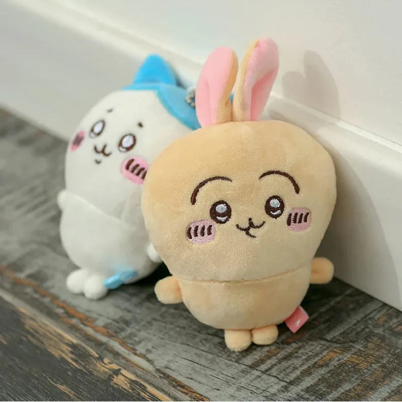 A soft, light yellow Chiikawa Usagi plush keychain charm with pink ears and a blue backpack accessory.