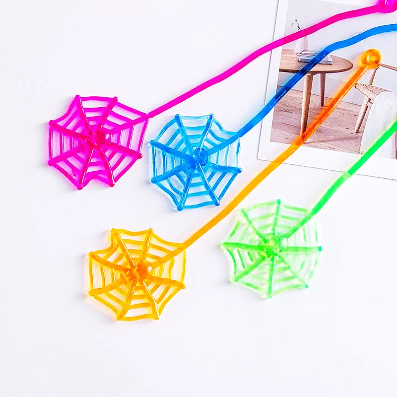 Colorful stretchy spider web toys with neon pink, blue, yellow, and green strings.