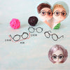 A collection of five metal round glasses frames, including a pair on a doll's face and several separate frames.