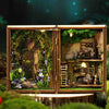 A wooden miniature dollhouse kit featuring a detailed diorama with greenery, furniture, and lighting elements.