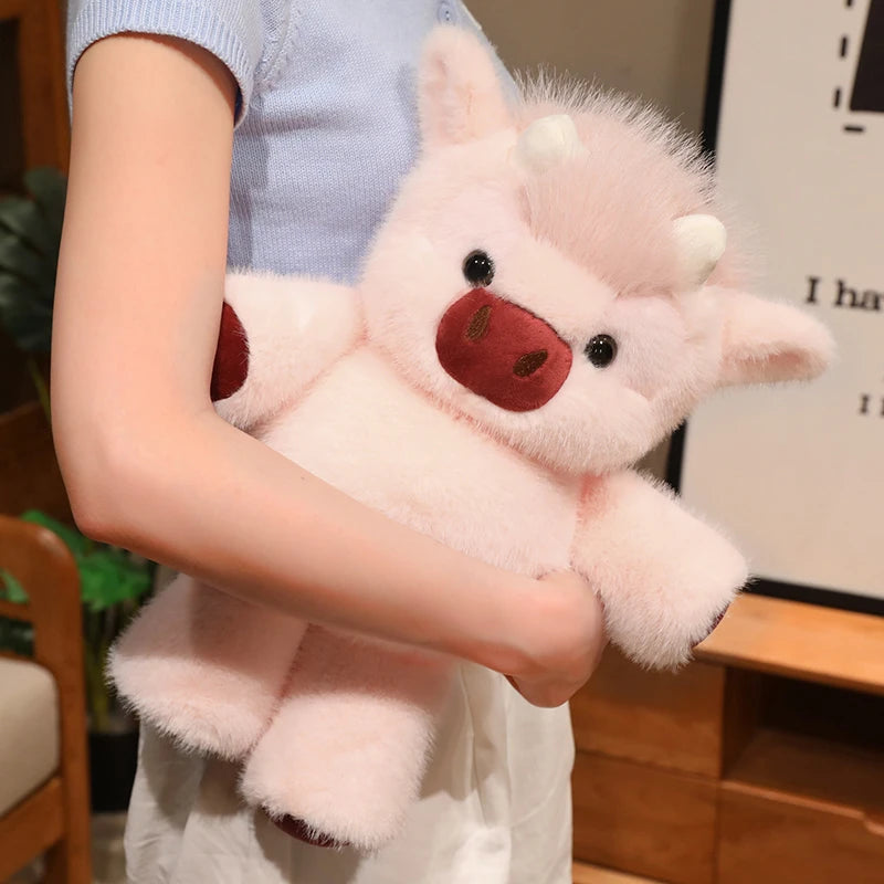 A person is holding a pink West Highland calf plush toy with white horns and a brown nose.
