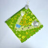 A green felt mat featuring a yellow floral pattern and small white animal plush toys.