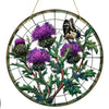 A round acrylic window hanging featuring purple Scottish thistles and a black butterfly against a dark green background.
