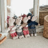 A collection of handmade mouse plush dolls dressed in various retro outfits standing in a bright room.
