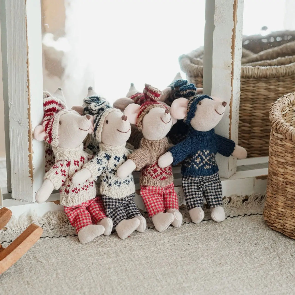A collection of handmade mouse plush dolls dressed in various retro outfits standing in a bright room.