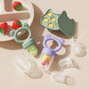 A silicone baby fruit feeder set with green and purple molds and feeding accessories on a light background.
