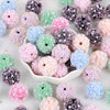 A collection of pink, purple, and blue rose flower ball acrylic beads for jewelry making.