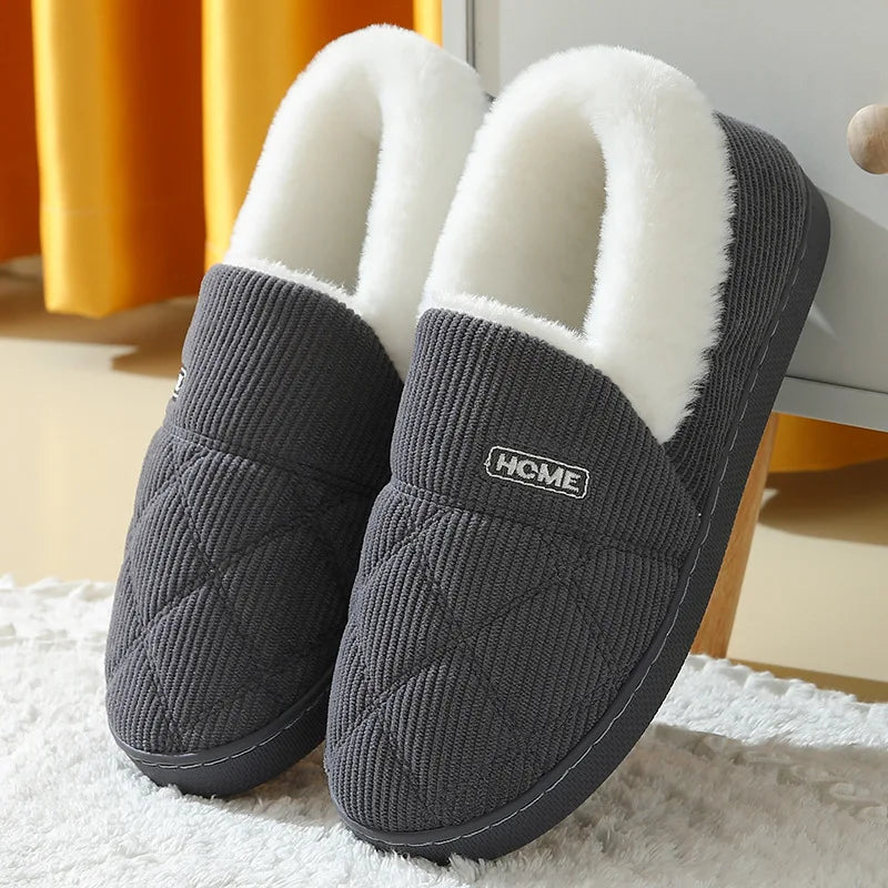 A pair of gray knitted slippers with white faux fur lining resting on a white surface.