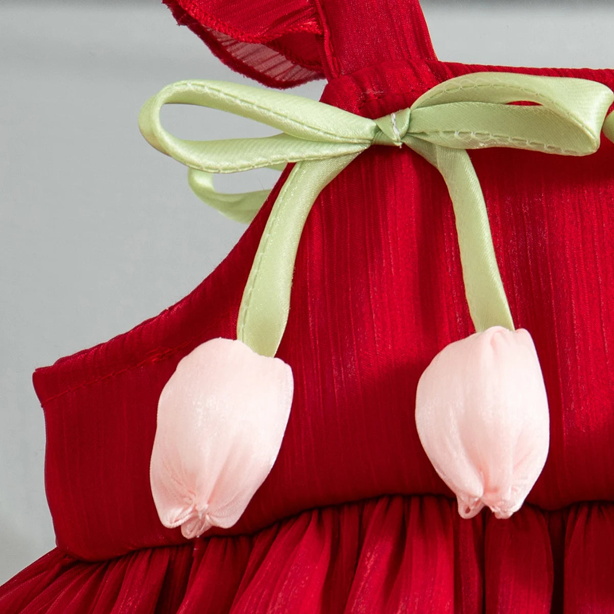 Red dress with a light green bow and pink fabric flowers on the bodice