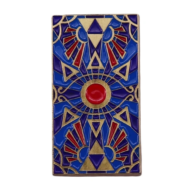 A colorful enamel pin brooch featuring a geometric design with radiating sunbursts and an eye motif.