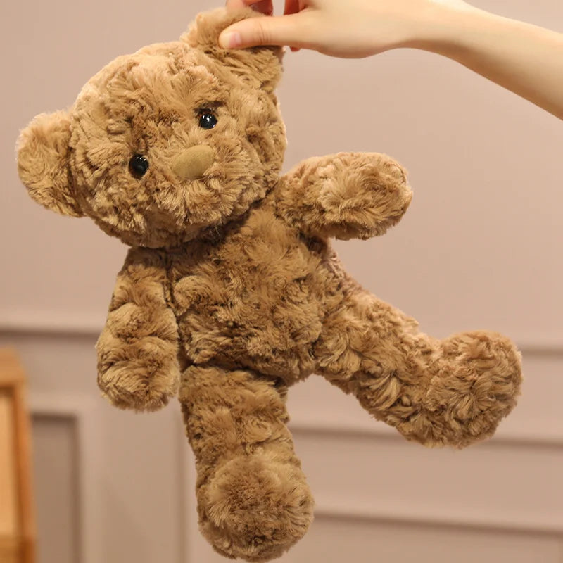 A brown teddy bear plush toy being held by a hand, showing its soft texture and cuddly appearance.