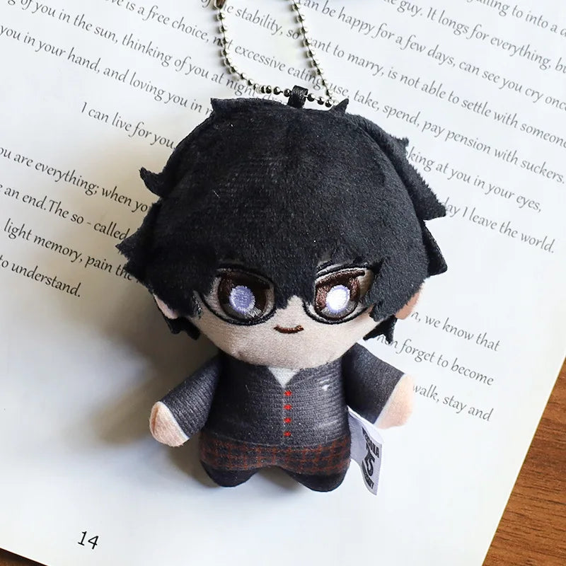 A black anime character plushie pendant charm with large purple eyes and dark hair resting on a piece of paper.