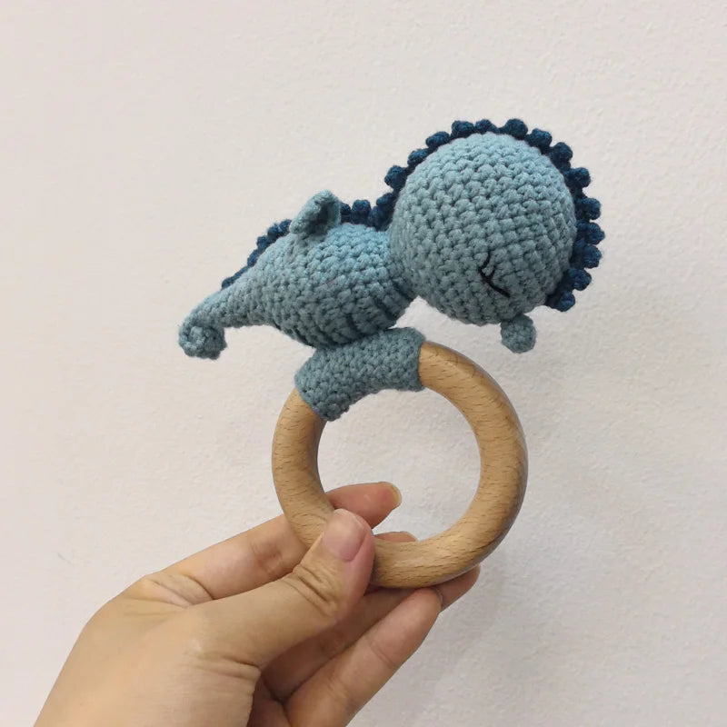 A handmade wooden baby rattle and teether ring featuring a blue textured silicone or fabric head attached to a natural wood r