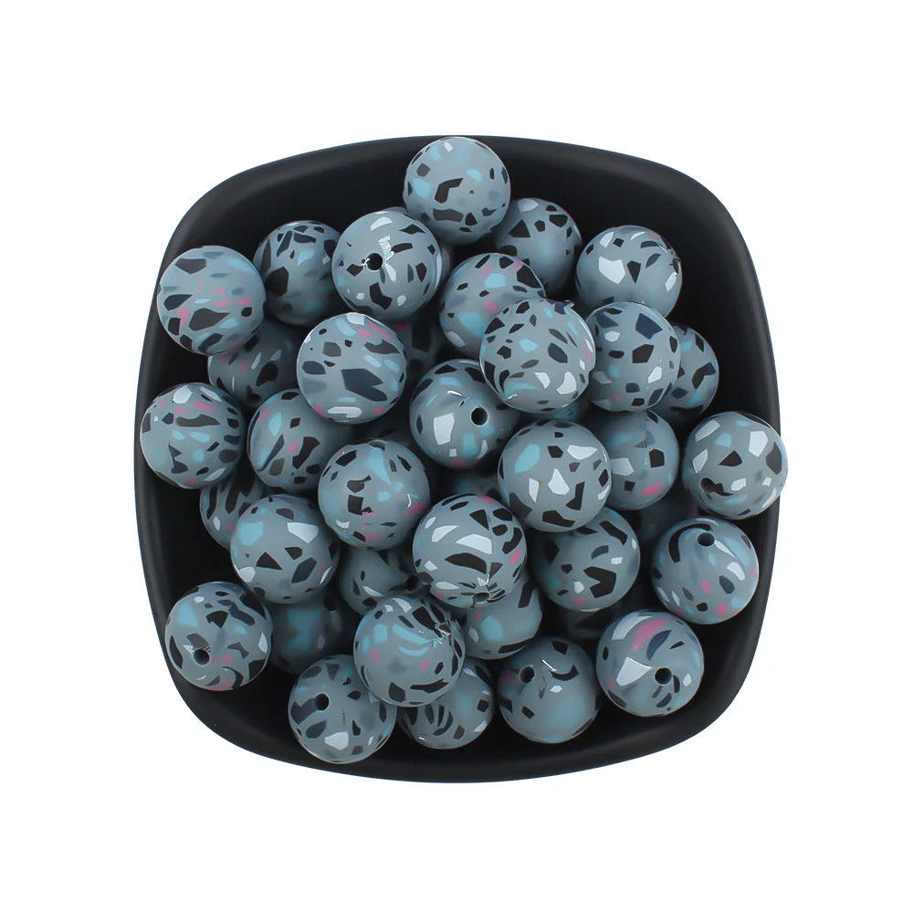 A black bowl filled with small, round silicone beads featuring a leopard and daisy print in shades of blue and gray.