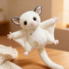 A white plush mouse with large ears and a golden crescent moon design is shown on a wooden surface.