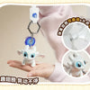 A white Toothless dragon keychain with movable wings and glowing eyes is displayed on a person's hand.