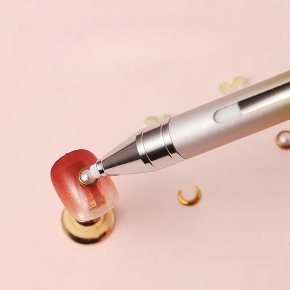 A silver gradient rotating dotting pen is shown applying a colored substance to a nail or craft item.