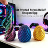 Three 3D printed dragon egg fidget spinners in purple, blue, and gold colors displayed on a white surface.