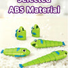 Several green plastic fish toys are displayed on a white surface with small white beads.