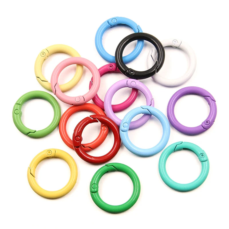 A collection of ten colorful metal O-ring spring clasps in various colors like blue, pink, black, and green.