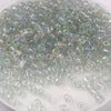 A pile of iridescent, multi-colored glass rice beads for DIY jewelry and crafting.