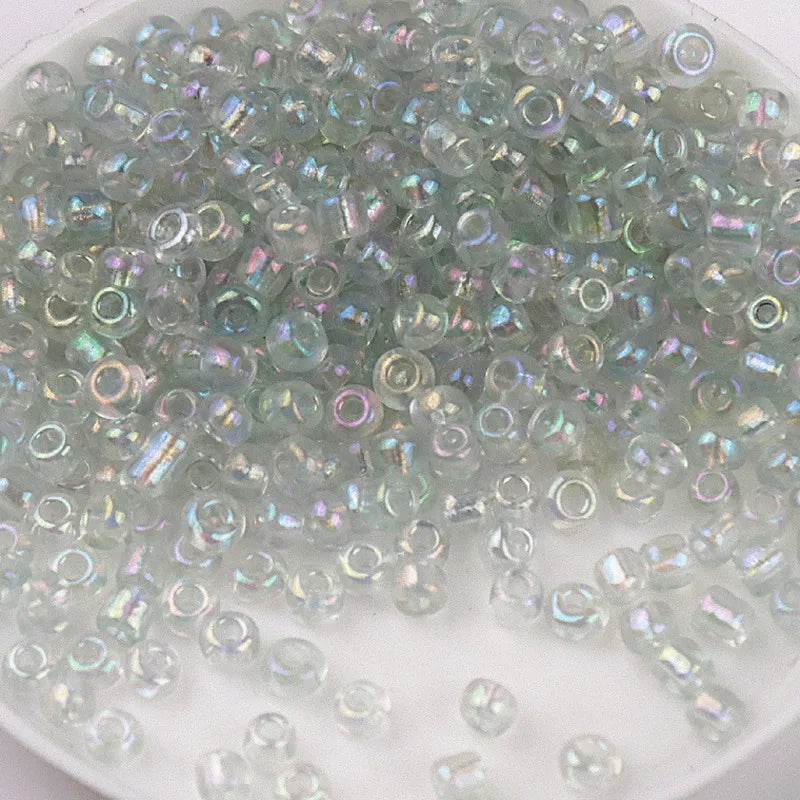 A pile of iridescent, multi-colored glass rice beads for DIY jewelry and crafting.
