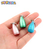 A hand holds a miniature alloy kettle in pink and green colors for dollhouse kitchen decor.