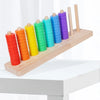 A wooden ring toss game with colorful stacking rings in a gradient of red, orange, yellow, green, blue, and purple.